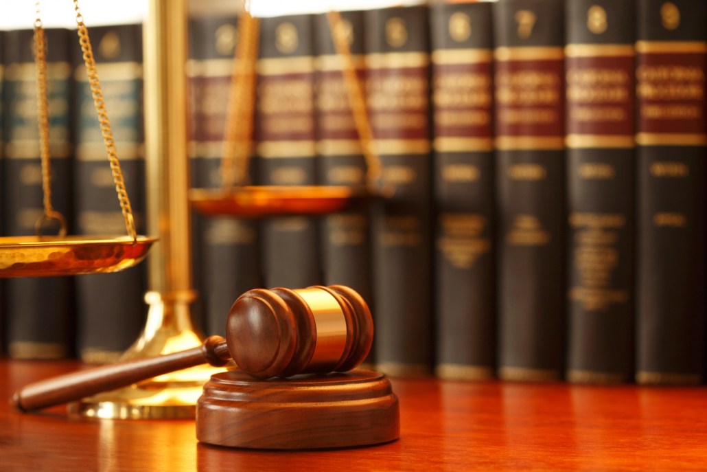 Traditional wooden judge's gavel with gold scales of justice and law books